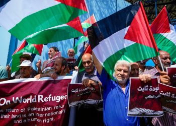 Palestinian refugees hold placards in Arabic that read "The right of return is fixed," and wave Palestinian flags during a sit-in marking the World Refugee Day in front of UNRWA office in Beirut, Lebanon, Tuesday, June 20, 2023.(AP Photo/Hassan Ammar)
