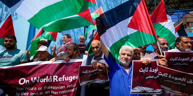 Palestinian refugees hold placards in Arabic that read "The right of return is fixed," and wave Palestinian flags during a sit-in marking the World Refugee Day in front of UNRWA office in Beirut, Lebanon, Tuesday, June 20, 2023.(AP Photo/Hassan Ammar)