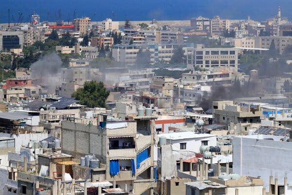 Densely packed buildings in a Palestinian refugee camp in Lebanon, with smoke rising above some of them.