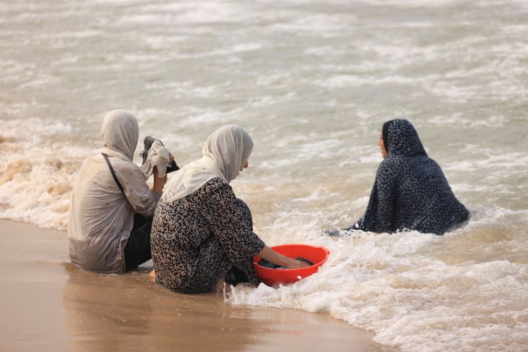 Palestinian women wash their clothes using sea water due to the lack of fresh water and electricity, along the beach in Deir el-Balah