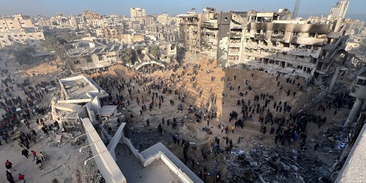 Palestinians gather around the burned and destroyed Al-Shifa Hospital