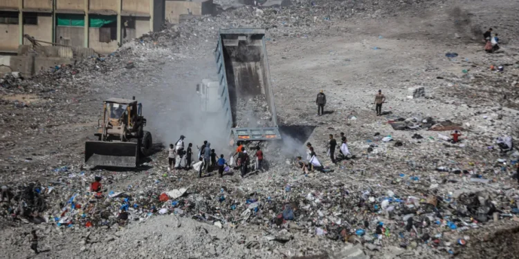 Anak-anak Palestina mencari barang-barang yang masih layak pakai di antara tumpukan sampah dan puing di Kota Gaza, Gaza, pada 21 Oktober 2025. [Hamza ZH Qraiqea – Anadolu Agency]