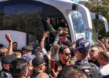 Tawanan yang dibebaskan di Tepi Barat membuat simbol kebebasan dengan jarinya (The Guardian)