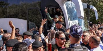 Tawanan yang dibebaskan di Tepi Barat membuat simbol kebebasan dengan jarinya (The Guardian)