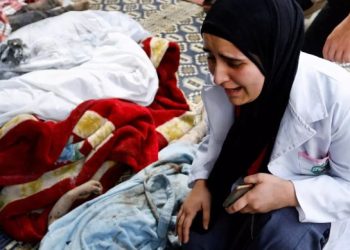 Seorang perempuan menangis di samping jasad anak-anak yang menjadi korban serangan Israel (MEE)