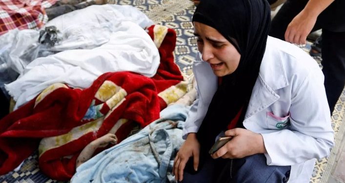 Seorang perempuan menangis di samping jasad anak-anak yang menjadi korban serangan Israel (MEE)