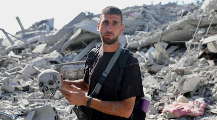 Pria Palestina memegang tengkorak yang ia temukan di reruntuhan rumahnya di Kota Gaza (MEE)