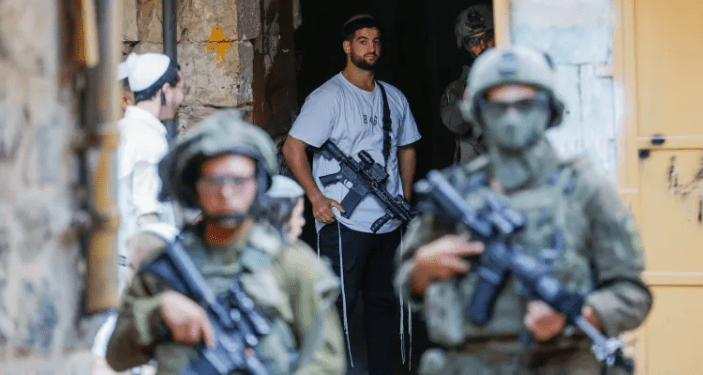 Tentara Israel melindungi pemukim ilegal yang membawa senjata di Hebron, Tepi Barat (Al Jazeera)