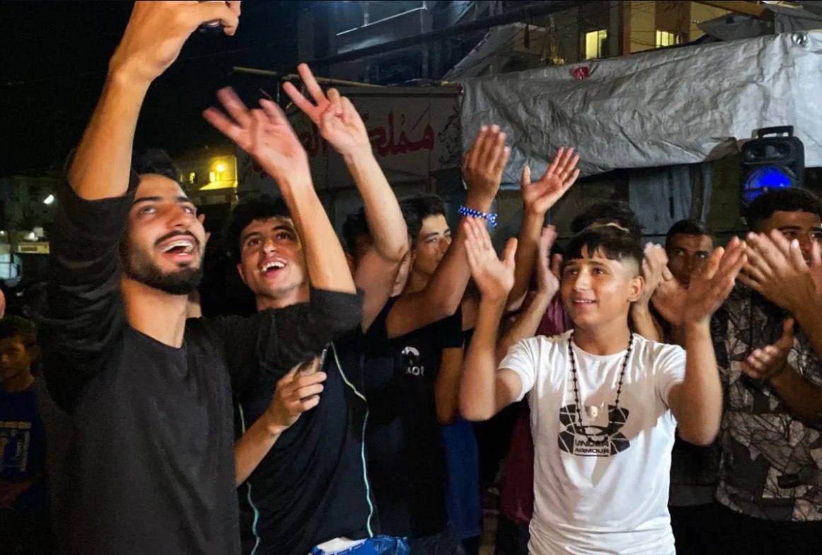 Para pemuda Palestina di Khan Younis bersuka cita saat disiarkannya berita tentang perjanjian gencatan senjata baru untuk Gaza (9/10). Presiden AS Donald Trump mengumumkan bahwa Israel dan Hamas telah mencapai kesepakatan mengenai fase pertama gencatan senjata Gaza, setelah beberapa hari negosiasi yang dimediasi di Mesir. (AFP)