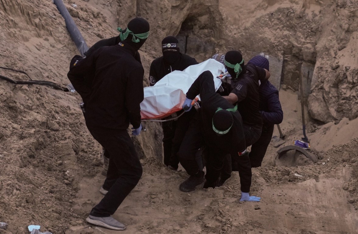 Sayap militer Hamas membawa tas putih yang diyakini berisi jenazah Israel, setelah mengambilnya dari terowongan saat mencari jenazah sandera di Kota Hamad, Khan Younis, di Gaza selatan, Selasa, 28 Oktober 2025. (Jehad Alshrafi/AP)