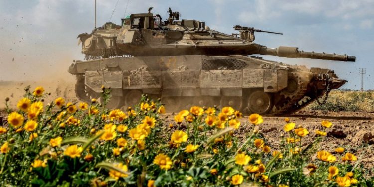 Tank Israel melewati jalan dengan bunga-bunga liar di dekat perbatasan Gaza (The Guardian)