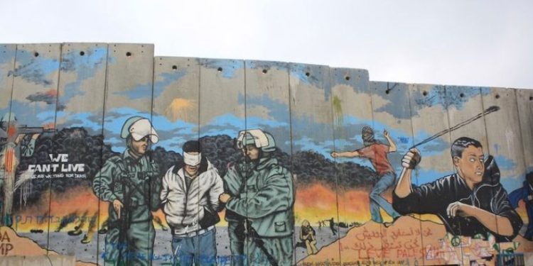 tembok apartheid dan grafiti perjuangan Palestina (Harvard International Review).
