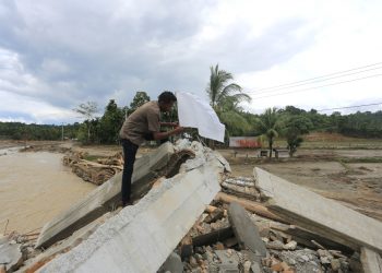 Seorang warga memasang bendera putih di depan rumahnya yang rusak pada 17 Desember 2025, setelah banjir besar di desa Jambak, distrik Pante Ceureumen, Aceh Barat, Aceh. Bendera putih tersebut dikibarkan oleh warga desa untuk menyerukan kepada pemerintah agar segera menyatakan bencana di Sumatera sebagai bencana nasional, yang akan memungkinkan bantuan internasional masuk dan membantu mempercepat upaya pemulihan. (Antara/Syifa Yulinnas)