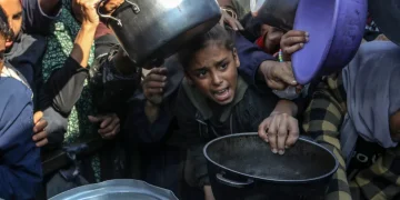 Para pengungsi Palestina yang berjuang melawan kelaparan menunggu untuk menerima makanan hangat yang dibagikan oleh organisasi amal, di wilayah al-Mawasi, Khan Yunis, Gaza pada 17 Desember 2025. [Abed Rahim Khatib – Anadolu Agency]