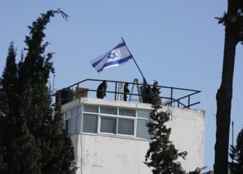 Polisi dan pejabat Israel mengibarkan bendera Israel di kompleks badan Perserikatan Bangsa-Bangsa untuk pengungsi Palestina di Yerusalem Timur, setelah polisi Israel secara paksa memasuki kompleks tersebut pada hari Senin. (Mahmoud Illean / Associated Press)