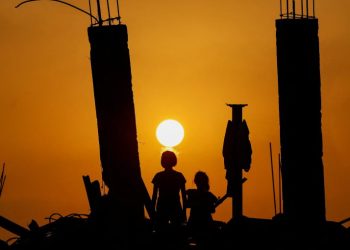 Anak-anak Palestina melihat matahari terbenam dari reruntuhan di Jabalia, Gaza (Reuters)