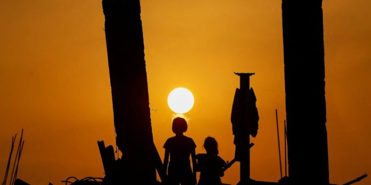 Anak-anak Palestina melihat matahari terbenam dari reruntuhan di Jabalia, Gaza (Reuters)