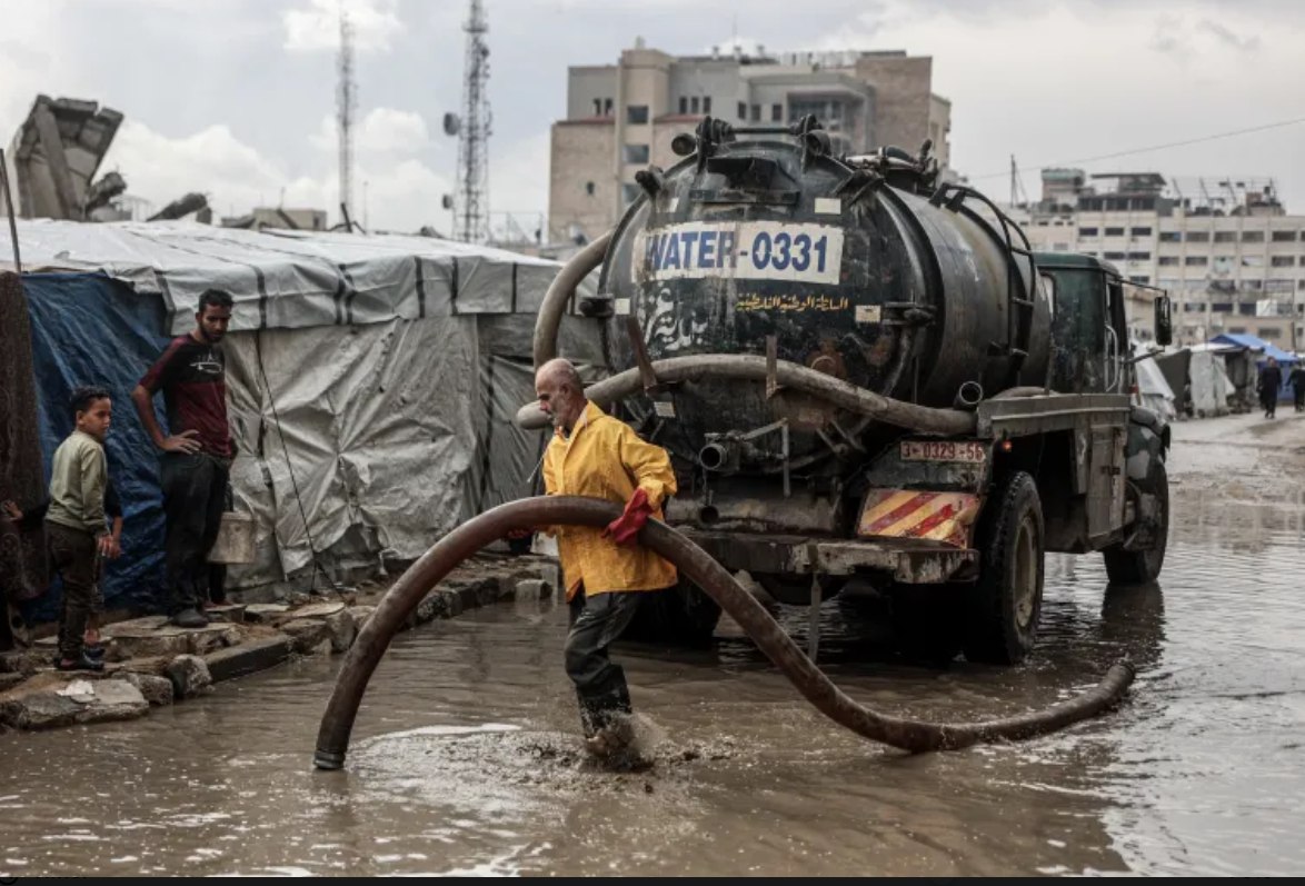 Seorang pria Palestina membersihkan genangan air dari jalan dekat kamp pengungsian setelah hujan musim dingin pertama di Kota Gaza (14/11). Para pengungsi di Gaza kembali terguncang setelah hujan deras membanjiri tenda-tenda mereka di kamp-kamp pengungsian. PBB memperingatkan bahwa blokade Israel telah menyebabkan ratusan ribu keluarga kehilangan tempat tinggal yang layak. (AFP)
