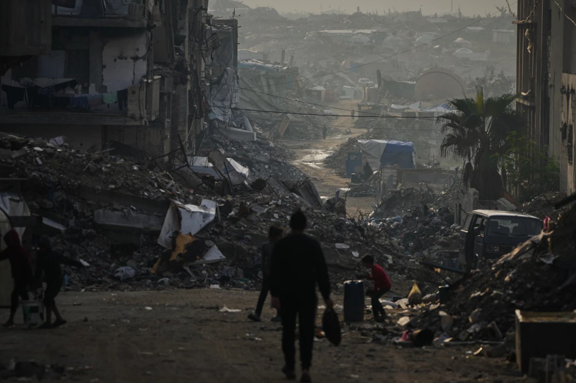Warga Palestina berjalan di tengah reruntuhan akibat serangan udara dan darat Israel di Kota Gaza (29/11). Jumlah warga Gaza yang terbunuh telah melampaui 70.000 jiwa. Angka ini terus meningkat meski dalam fase gencatan senjata akibat pelanggaran Israel. (Abdel Kareem Hana/ AP Photo)