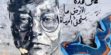 Sebuah grafiti dengan gambar sastrawan Palestina, Mahmoud Darwish, dan penggalan puisinya, “Di atas tanah ini ada hidup yang layak diperjuangkan”. (Zaina Zinati/Jordan News)