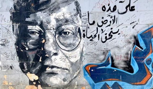 Sebuah grafiti dengan gambar sastrawan Palestina, Mahmoud Darwish, dan penggalan puisinya, “Di atas tanah ini ada hidup yang layak diperjuangkan”. (Zaina Zinati/Jordan News)