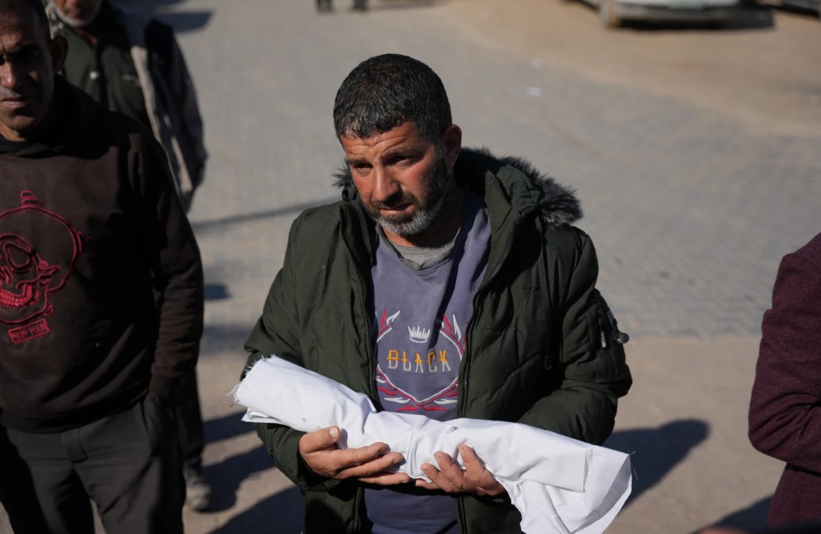 Eseid Abdeen, 42 tahun, menggendong jenazah putranya yang berusia 29 hari, Saeed, yang meninggal karena cuaca dingin (18/12). Bayi tersebut, yang lahir prematur dan sangat kekurangan berat badan, menjadi bayi kedua yang meninggal karena hipotermia dalam beberapa hari terakhir di Rumah Sakit Nasser. (Abdel Kareem Hana/ AP Photo/ Al Jazeera)