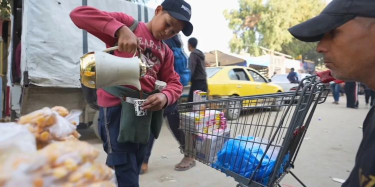 Sambil membawa termos logam di jalanan Kota Gaza, Mohammed Ashour (15 tahun) menjual kopi kepada para pejalan kaki (1/12). Ia meninggalkan pendidikannya setelah ayahnya terbunuh dalam genosida Israel dan sekarang menghidupi keluarganya sebagai pencari nafkah utama. Setidaknya 39.000 anak dilaporkan telah kehilangan satu atau kedua orang tua dan ekonomi di Gaza dan kehancuran yang meluas telah merampas sumber pendapatan lebih dari 80 persen angkatan kerja, (Al Jazeera/Truthout)
