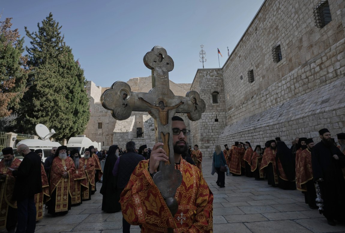 Para pemuka agama bersiap menyambut kedatangan Patriark Ortodoks Yunani Al-Quds, Theophilos III ke Gereja Kelahiran, yang secara tradisional diyakini sebagai tempat kelahiran Yesus Kristus, untuk merayakan Natal menurut kalender Ortodoks Timur, di Betlehem, Tepi Barat yang diduduki (7/1). Perayaan Natal kembali pada tahun ini ke Alun-Alun Manger bersejarah di Betlehem setelah absen selama dua tahun. (Mahmoud Illean/AP Photo/ Al Jazeera/ Anadolu/ MEMO)