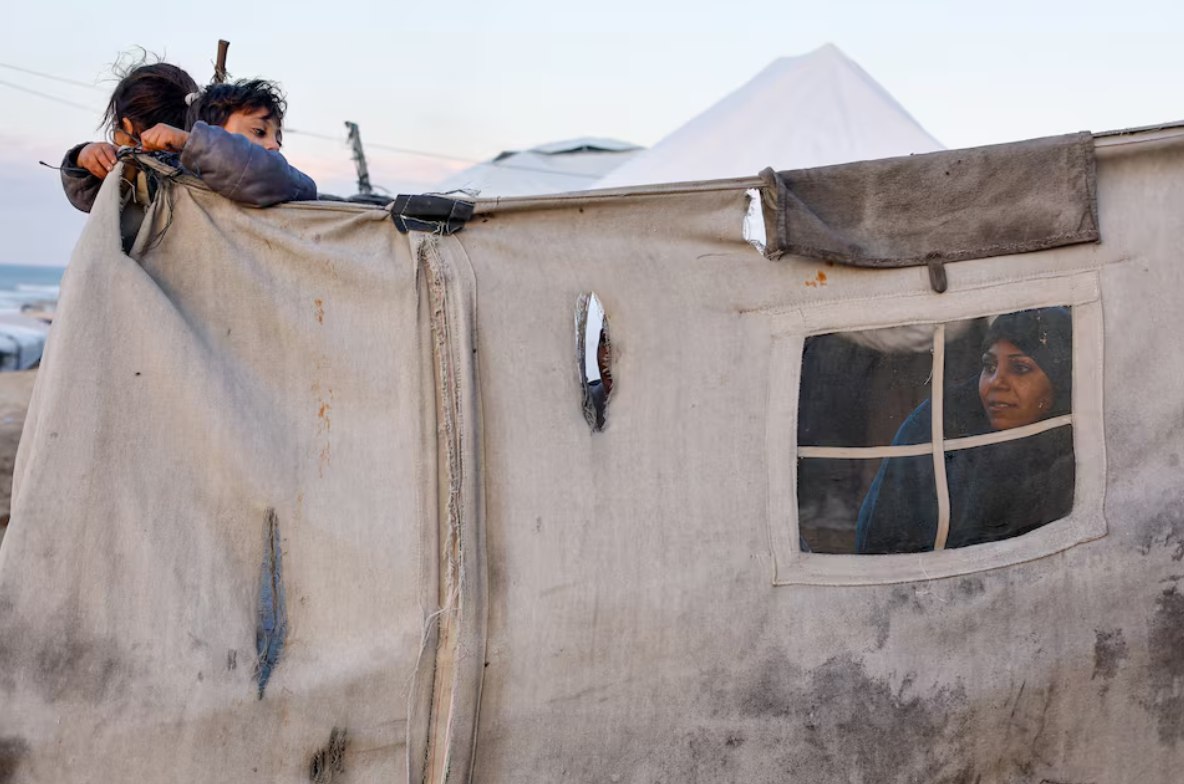 Keluarga Palestina yang mengungsi tampak berlindung di tenda pengungsian di Deir al-Balah, Jalur Gaza tengah (19/1). Di bawah blokade ketat Israel dan perluasan garis kuning yang mencaplok wilayah Gaza, hampir seluruh penduduk yang berjumlah lebih dari dua juta orang kini terkurung di sekitar sepertiga wilayah Gaza. (Mahmoud Issa/ Reuters/ Tribune)