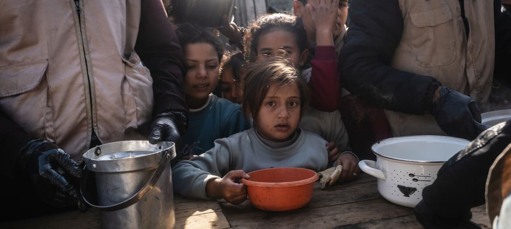 Anak-anak menunggu makanan hangat di dapur umum yang didukung Program Pangan Dunia/WFP di Khan Younis, Gaza (21/1). Wakil Juru Bicara PBB Farhan Haq mengatakan bahwa sejak awal tahun, lebih dari 860.000 orang telah menerima paket makanan yang didistribusikan melalui 50 titik distribusi. (Maxime Le Lijour/ WFP)