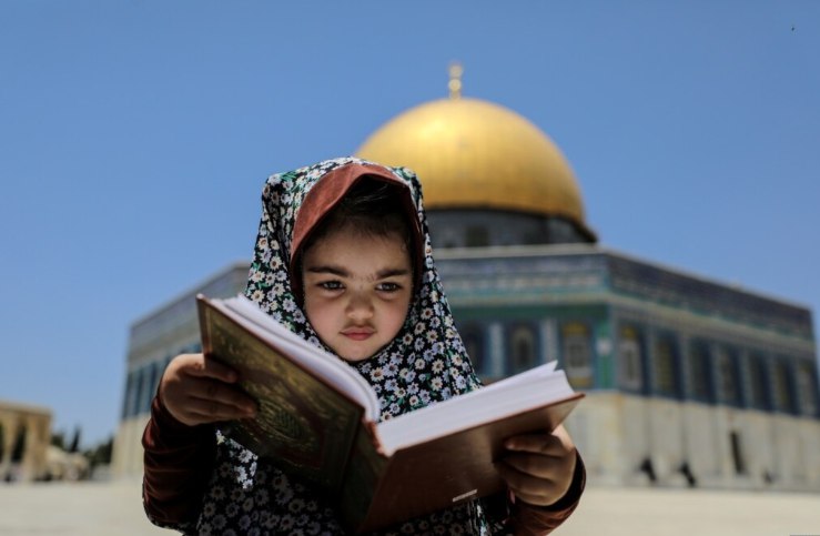 Seorang anak perempuan duduk sambil mengaji Al-Qur’an di kompleks Masjid al-Aqsa. (Foto: Reuters)