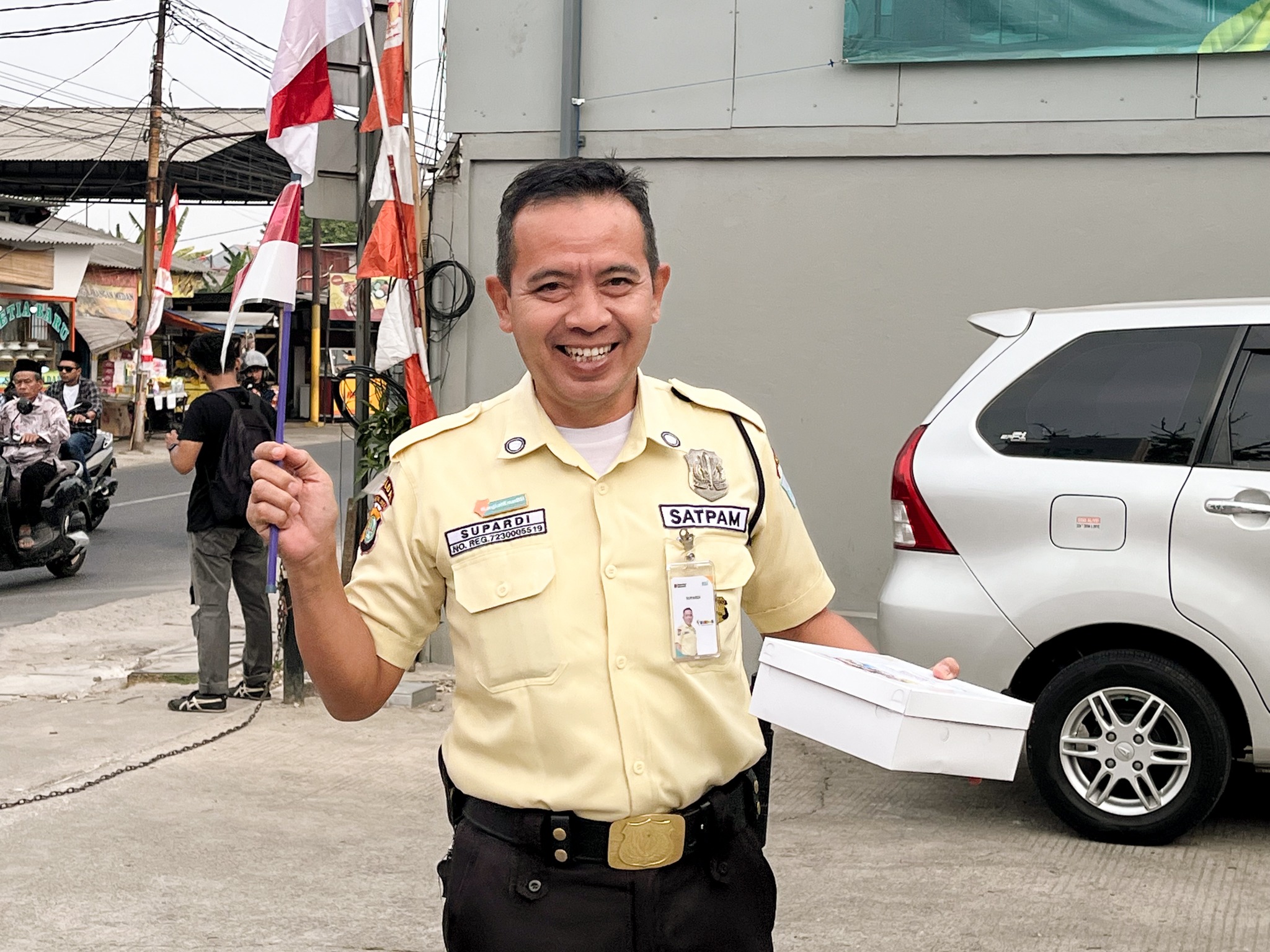 Satpam kantor menerima nasi kotak sekaligus mengangkat bendera untuk peringati HUT ke-81 RI.
